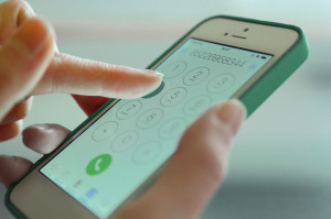 Finger touch number on smartphone to make a call, close up