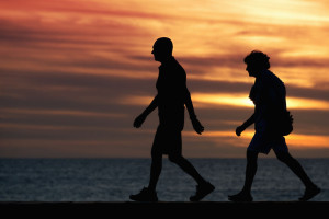 67133516 - seniors walking brisk walk along the shore at sunset